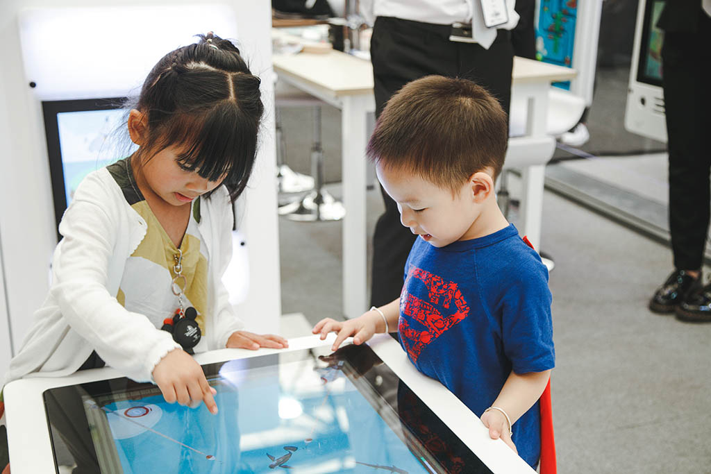 Dwoje dzieci zajętych zabawą z interaktywnymi systemami gier IKC